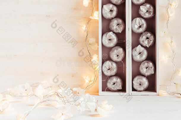 圣诞软家居装饰的银苹果和灯燃烧在盒子在一个木制的白色背景。