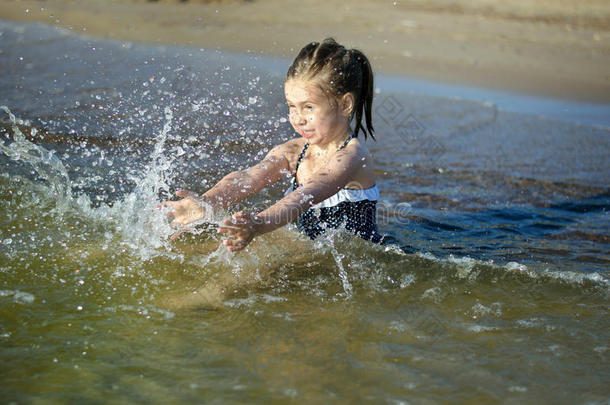 可爱的小女孩正在溅水，打碎海水，玩得很开心
