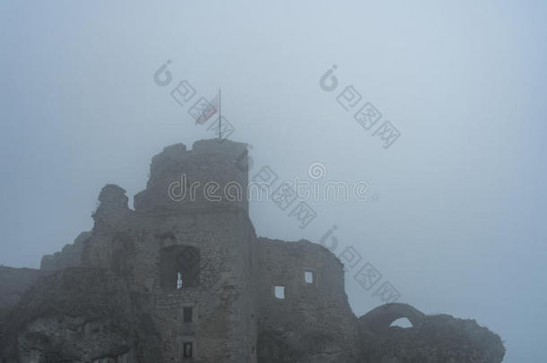 在浓雾中中世纪城堡废墟顶部的旗帜
