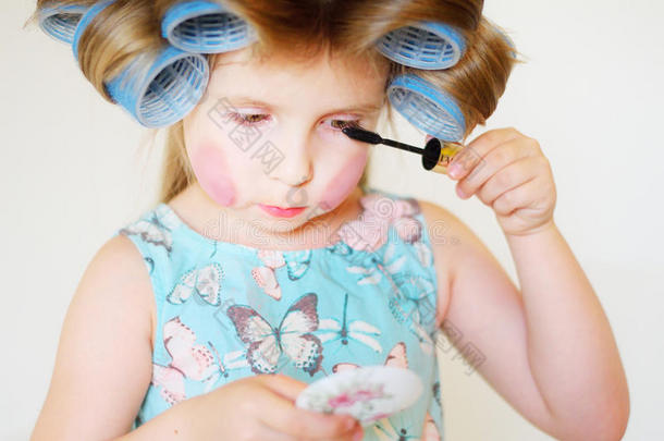 可爱有趣的小女孩用妈妈化妆品化妆