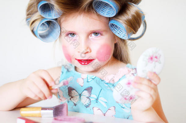 可爱有趣的小女孩用妈妈化妆品化妆