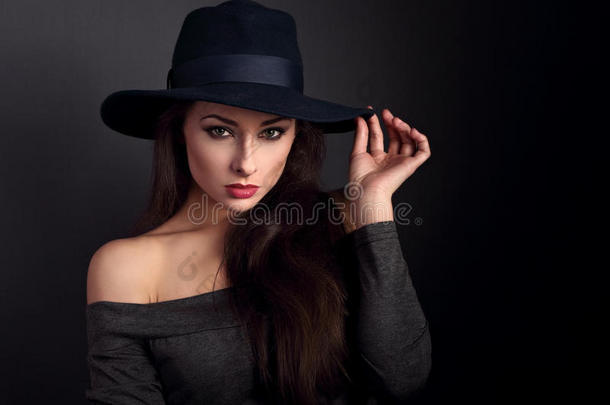 优雅的化妆女子戴着<strong>时尚帽子</strong>，在黑影背景上摆姿势。 特写肖像