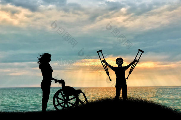 在轮椅旁边用拐杖残疾的儿童和海滩上的护士