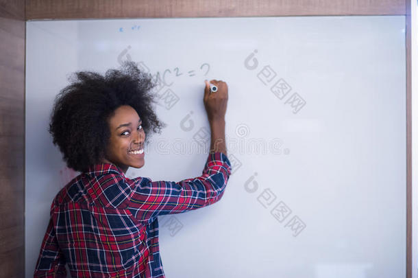 一位非洲裔美国妇女在现代<strong>办公</strong>室的<strong>黑板</strong>上写字