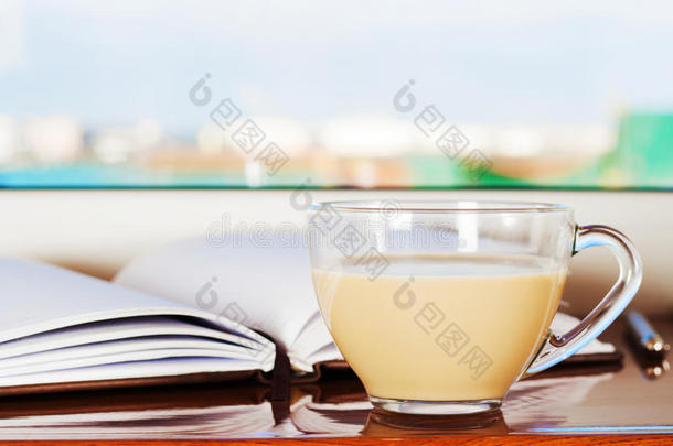 清晨，一杯带牛<strong>奶</strong>的<strong>咖</strong>啡和一个记事本躺在靠近窗户的窗台上。