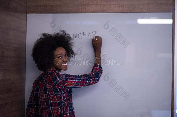 一位非洲裔美国妇女在现代<strong>办公</strong>室的<strong>黑板</strong>上写字