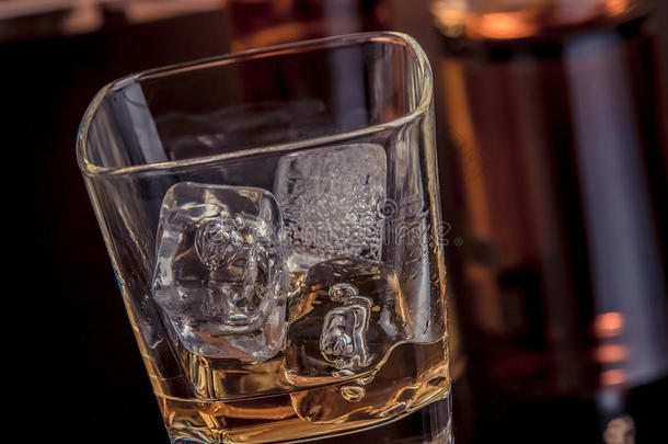 特写威士忌与<strong>冰块</strong>在玻璃附近的瓶子黑色<strong>背景</strong>，温暖的气氛