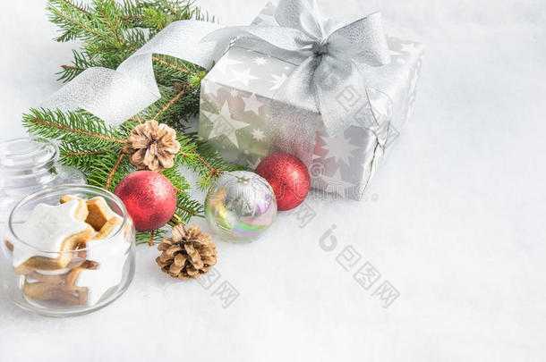 圣诞礼品盒，银色包装纸，白色蓬松的背景。 一个装满明星饼干和圣诞装饰的罐子。