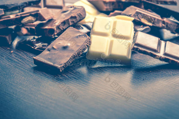 一堆巧克力的特写镜头，背景是深色的木头。黑巧克力、牛奶巧克力、白巧克力和坚果巧克力。复制空间。