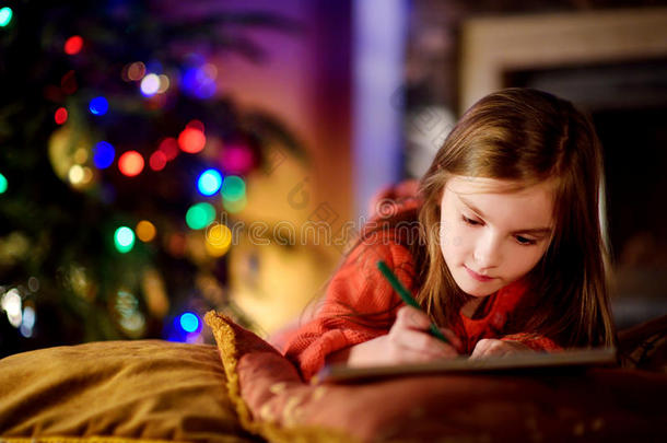 可爱的小女孩在圣诞节的壁炉旁给圣诞老人写了<strong>一封信</strong>