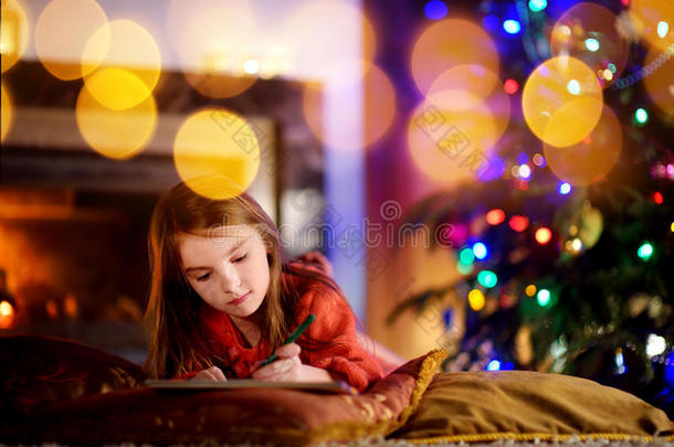 可爱<strong>的</strong>小女孩在圣诞节<strong>的</strong>壁炉旁给圣诞老人写了<strong>一封信</strong>