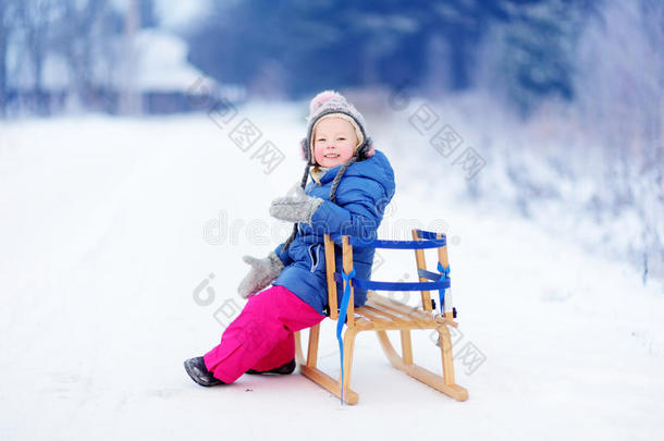 有趣的小女孩在冬天的公园玩雪橇