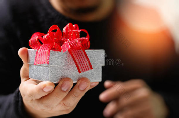 送礼，男人用手拿着礼品盒，以示送礼。模糊的背景，博克效应