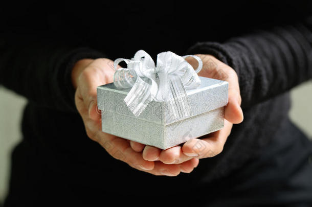 送礼，男人用手拿着礼品盒，以表示送礼的姿态。模糊的背景，效应，复古