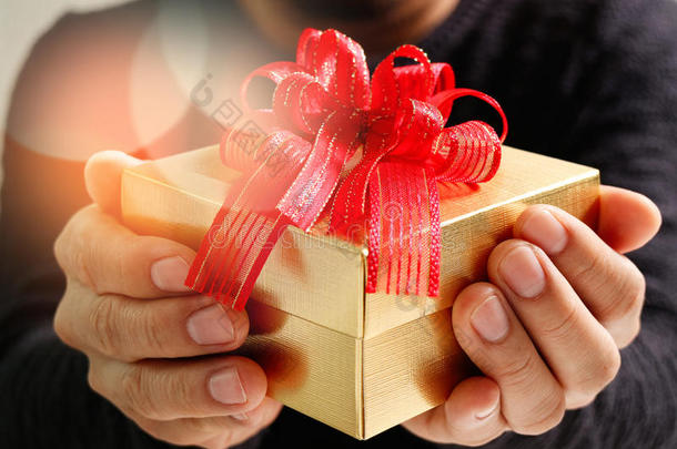 送礼，男人用手拿着礼品盒，以表示送礼的姿态。模糊的背景