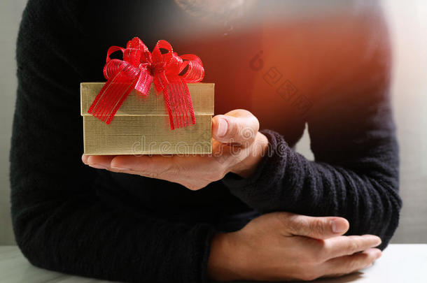 送礼，男人用手拿着礼品盒，以表示送礼。模糊的背景