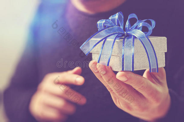 送礼，男人用手拿着礼品盒，以表示送礼的姿态。模糊的背景