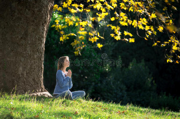 秋天，女孩坐在枫树下的草地上沉思