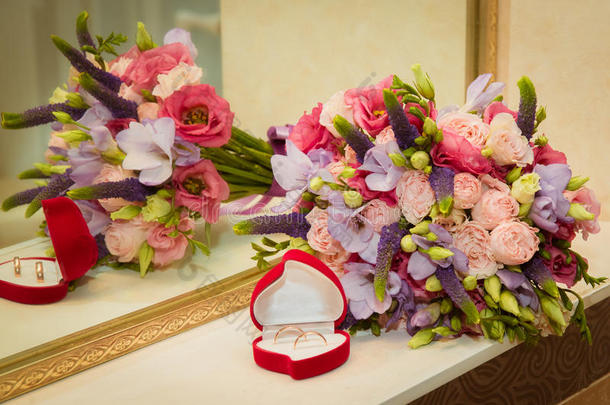 新娘花束和两个结婚戒指在红色的盒子里，形状像一颗心。