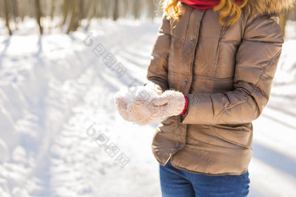 特写女人手里拿着天然柔软的白雪，做一个雪球，在寒冷的冬天微笑着