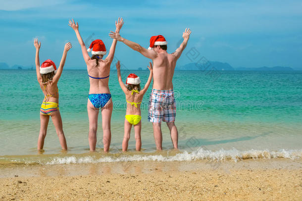 家庭假期在圣诞节和新年假期，快乐的父母和孩子在圣诞帽在海滩上玩得很开心