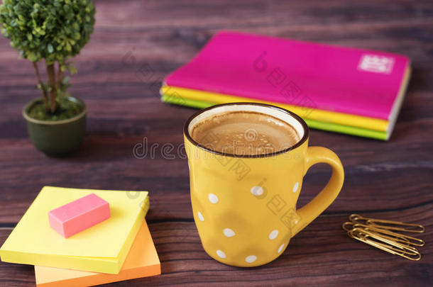 一杯咖啡。 黄色的一杯<strong>白点</strong>。 围绕办公桌面用品明亮，霓虹灯颜色-笔记本，金针，贴纸
