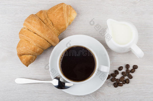 咖啡，牛角面包，牛奶罐和咖啡豆在桌子上