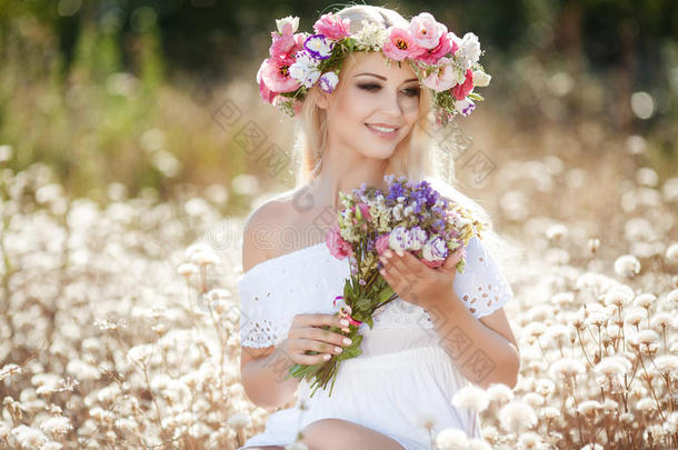 美丽的女人，在夏天的田野戴着花圈