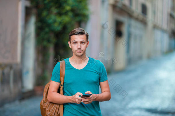 高加索男孩在街上拿着手机。 使用移动智能手机的人。
