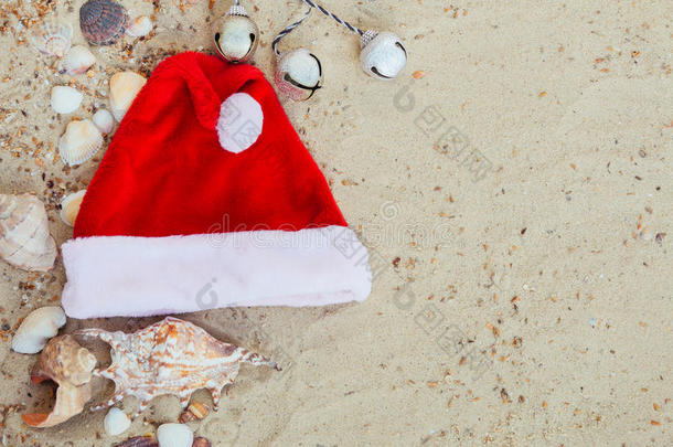 海滩上的圣诞帽。 在贝壳附近的沙子上圣诞老人。 假期。 新年假期。 复制空间。 框架。 上面的风景。