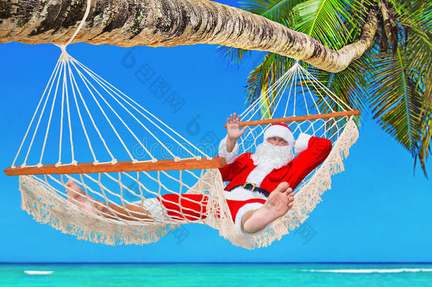 圣诞老人在热带棕榈海滩的吊床上日光浴