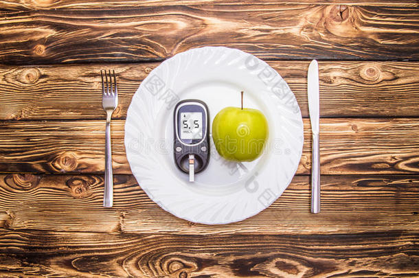 苹果和血糖仪测量盘子上的血糖，正确健康饮食的概念
