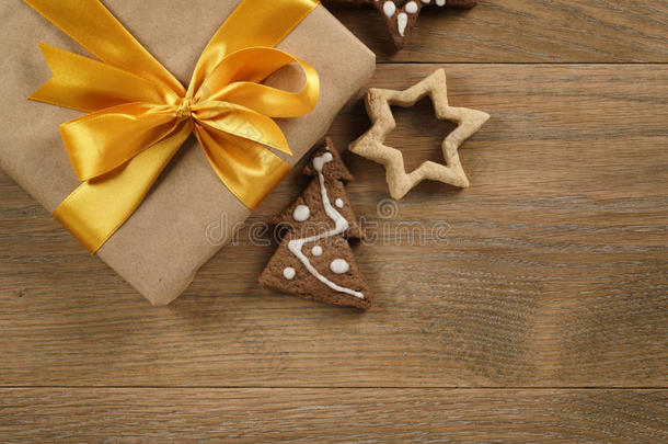 木桌上有<strong>金色</strong>丝带<strong>蝴蝶结</strong>和圣诞饼干的礼品盒