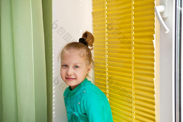 漂亮的女孩坐在窗户边，黄色的水平百叶窗