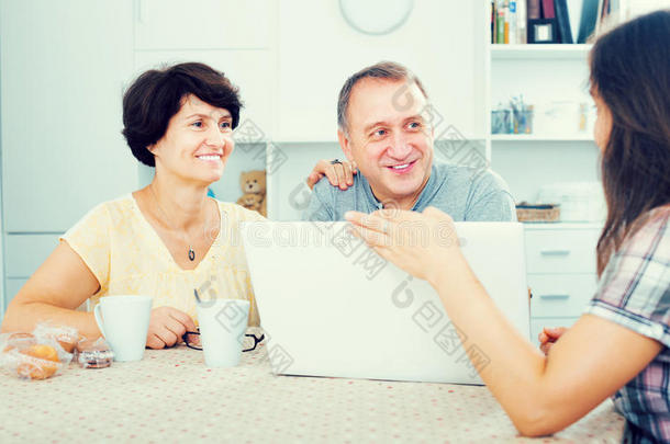 女儿在笔记本电脑上向她的父母<strong>展示文件</strong>
