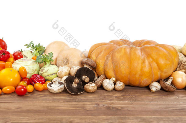 秋菜丰收在木桌上，白底。南瓜、西葫芦、土豆、洋葱和其他蔬菜。