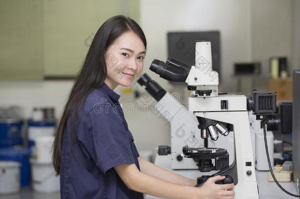 在实验室显微镜中观察显微镜的女科学家