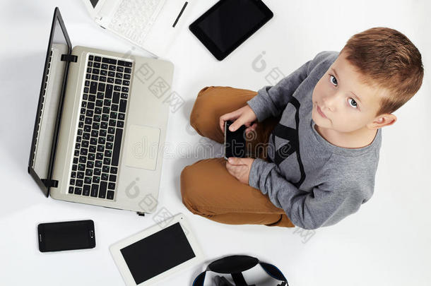 时尚的孩子周围有电脑，平板电脑，手机，小玩意