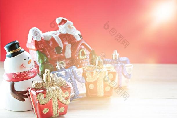 可爱的<strong>雪人</strong>，圣诞礼物盒或礼物和圣诞老人的<strong>房子</strong>在木头，红色背景