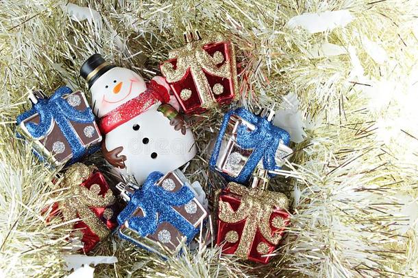 可爱的雪人和圣诞礼物盒或礼物上的金色流光或金属背景