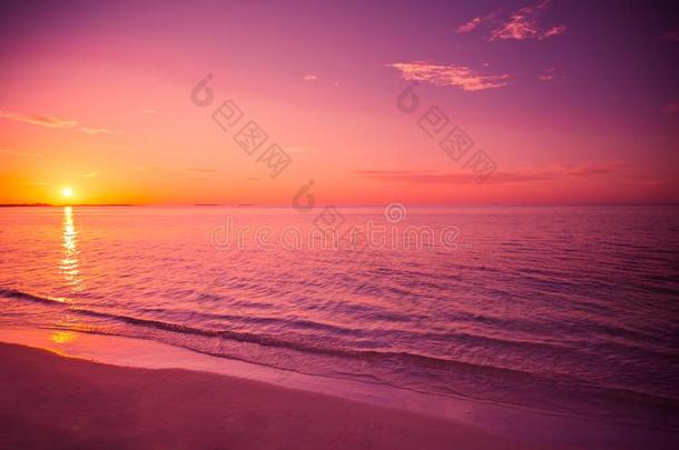 迷人的海滩日落。用柔和的波浪放松色彩