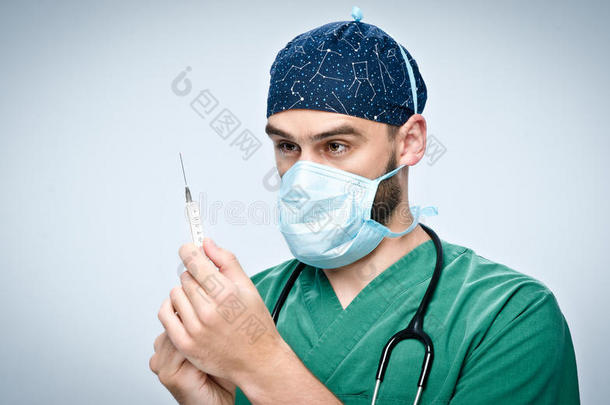 戴口罩和帽子的医生拿着带药的注射器。