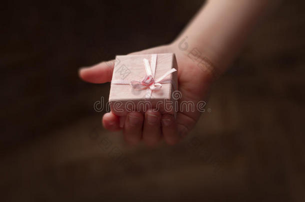 孩子的手拿着一个粉红色的小礼品盒