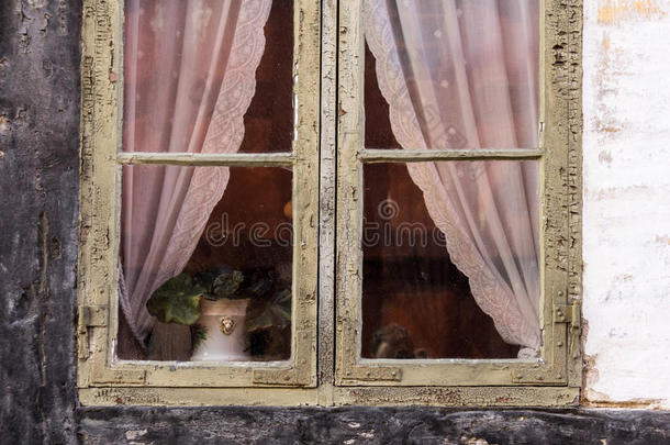 旧复古窗户的细节与裂缝和花边窗帘