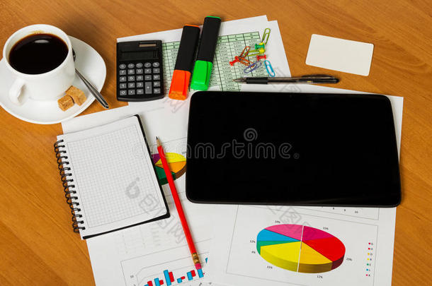 桌面背景上的数字平板电脑、计算器、咖啡、笔记本、办公用品。