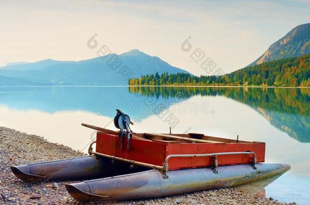 在阿尔卑斯山湖畔废弃的渔船。 秋天的早晨在湖边