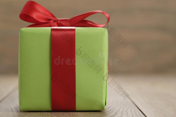 绿色纸礼盒，木制桌子上有经典的红色丝带蝴蝶结