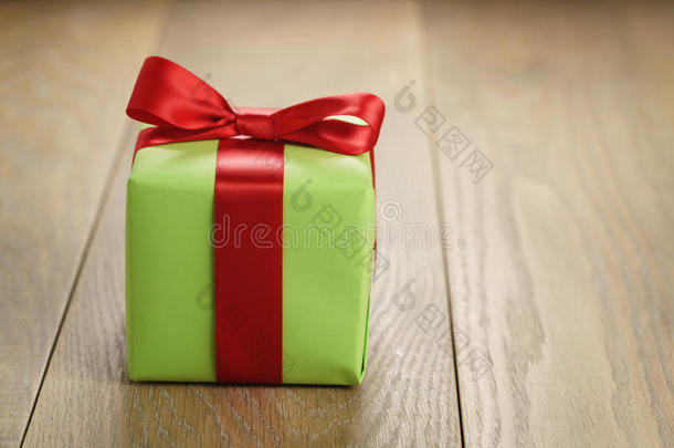 绿色纸礼盒，木制桌子上有经典的红色丝带蝴蝶结