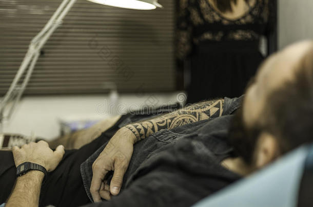 在纹身工作室关闭客户的部落纹身手臂