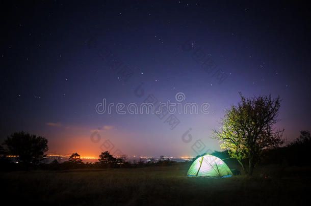 营地帐篷矗立在<strong>星空下</strong>的草地上，从那里闪闪发光